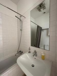 ein weißes Badezimmer mit einem Waschbecken und einem Spiegel in der Unterkunft Quarto no Chiado centro de Lisboa in Lissabon
