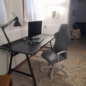 einen Schreibtisch mit einem Stuhl und einem Computer darauf in der Unterkunft Veneziacentopercento Apartments & Rooms in Venedig