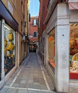 une ruelle dans une vieille ville avec des boutiques dans l'établissement Veneziacentopercento Apartments & Rooms, à Venise