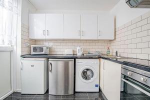 a kitchen with white cabinets and a washer and dryer at Superb 2 bedroom Flat in the Heart of Marylebone in London