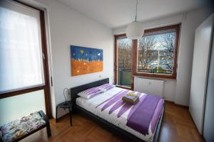 ein Schlafzimmer mit einem Bett mit violetter Bettwäsche und einem Fenster in der Unterkunft Lake Como Holiday Apartments in Como
