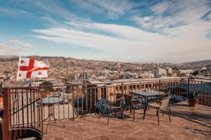 uma varanda com mesas e cadeiras e uma bandeira canadiana em Apartment on Borbalo 16 em Tbilisi