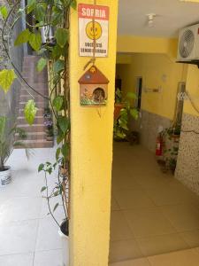 a yellow wall with a sign on it with a bird house at Residencial Morro de São Paulo in Morro de São Paulo