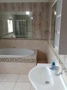 a bathroom with a tub and a sink and a mirror at Moonlight Guest House in Benoni