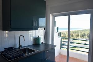 cocina con fregadero y vistas al océano en Beach House en Monte Gordo
