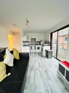 a living room with a black couch and a kitchen at Lovely 2 bedroom flat with free parking Flat 5 in Nottingham