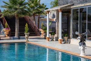 a swimming pool in front of a house with palm trees at Paradice Hotel Luxury Suites-Near zorbas Beach-FREE Breakfast in Stavros