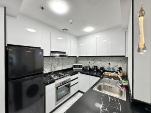a kitchen with white cabinets and a black refrigerator at Stay in heart of Dubai Marina walk to JBR beach in Dubai