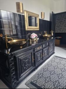 uma casa de banho preta com um lavatório e um espelho em La belle étoile em Bouniagues