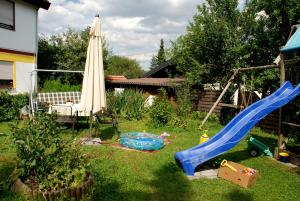 een speeltuin met een blauwe glijbaan en een paraplu bij Bantles Parterre Ferienwohnung in Bingen