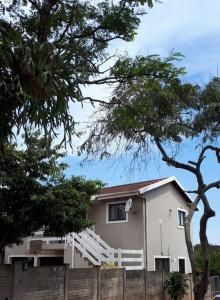 a white house with a fence and trees at Gorgeous Self Catering Cottage off Umhlanga Rocks in Durban