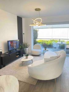 un soggiorno con divano bianco e TV di Luxury holiday house with jacuzzi and sauna a Ostenda