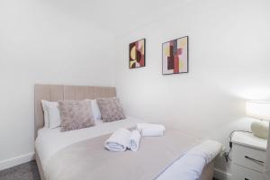 Un dormitorio blanco con una cama con toallas. en Stylish & Relaxing Retreat in Normanby, Sleeps 4, en Middlesbrough