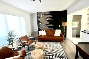 una sala de estar con un sofá de cuero marrón y sillas en OSU Retro Cottage Retreat in PNW, en Corvallis