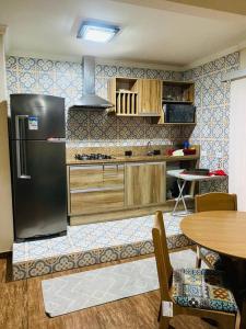 a kitchen with a refrigerator and a table at Sobrado Apartamento de Praia in Pontal do Paraná