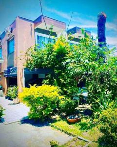 a yard with bushes and a building and a house at Sobrado Apartamento de Praia in Pontal do Paraná