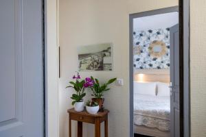 a bedroom with a bed and two potted plants at Hôtel de Lion sur Mer in Lion-sur-Mer