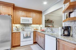 a kitchen with white appliances and wooden cabinets at Modern McCormick Townhome on Lake Thurmond! in McCormick
