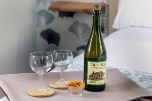 a bottle of wine and two glasses on a table at Hôtel de Lion sur Mer in Lion-sur-Mer