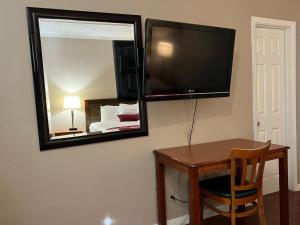 a room with a table and a mirror and a television at Hometown Inn North Hills in North Hills