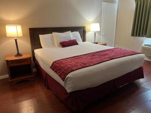 ein großes Bett in einem Hotelzimmer mit zwei Lampen in der Unterkunft Hometown Inn North Hills in North Hills