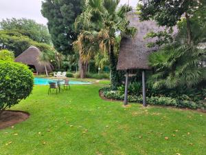 a resort yard with a pool and a thatch roof at Lipizzaner Lodge in Kyalami