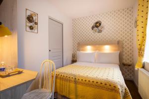 a small bedroom with a bed and a desk at Hôtel de Lion sur Mer in Lion-sur-Mer