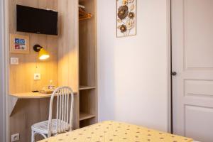 a room with a table and a chair and a desk at Hôtel de Lion sur Mer in Lion-sur-Mer