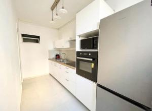 a kitchen with white cabinets and a black refrigerator at Suite Topaze by STACK  in Lyon