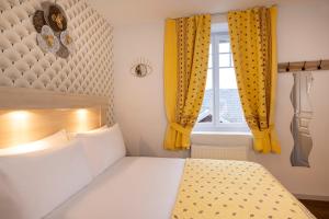 a bedroom with a bed and a window with yellow curtains at Hôtel de Lion sur Mer in Lion-sur-Mer