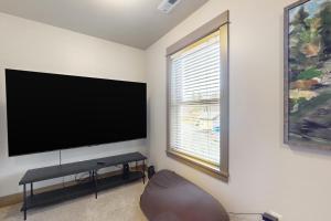 sala de estar con TV de pantalla plana grande en la pared en The McKenzie River House, en Vida