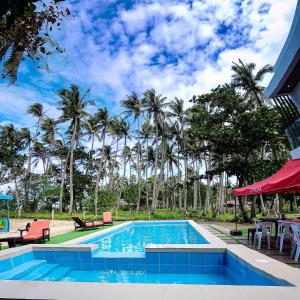 a swimming pool with chairs and palm trees at Saffire Beach Resort and Glamping in Pagudpud