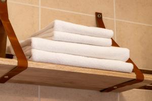 stos ręczników na drewnianym wieszaku w łazience w obiekcie Hôtel de Lion sur Mer w mieście Lion-sur-Mer