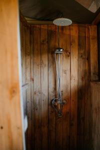 a shower head hanging on a wooden wall at Zawadi Camp in Serengeti