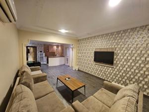ein Wohnzimmer mit einem Sofa und einem TV in der Unterkunft ليله ود للشقق المخدومة - Laylt wed in Dschidda