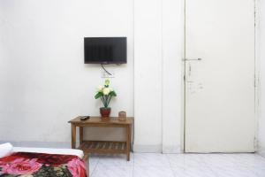 uma sala de estar com uma mesa com uma televisão e flores em Hotel White House International (Near Dhaka Medical) em Daca