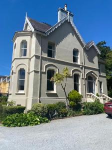 een wit huis met een palmboom ervoor bij Oakhurst Guesthouse in Cobh