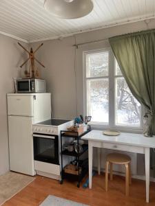 uma cozinha com um fogão, uma mesa e um micro-ondas em Small house central Parainen by Archipelago Trail em Pargas