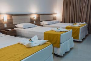 Habitación de hotel con 3 camas y toallas. en Milos Beach Hotel en Aquiraz