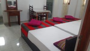 two beds in a room with purple and red pillows at Star Home Stay Bentota in Bentota