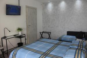 a bedroom with two beds and a tv on the wall at B&B Fili d'erba in Farra dʼlsonzo