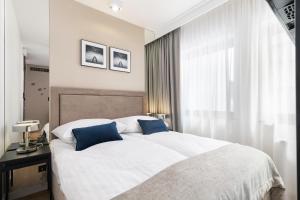 a bedroom with a large white bed with blue pillows at Apartamenty Deo Plaza - Old Town in Gdańsk