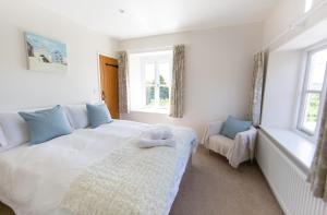 a bedroom with a white bed and two windows at Upper Vobster Farm in Radstock