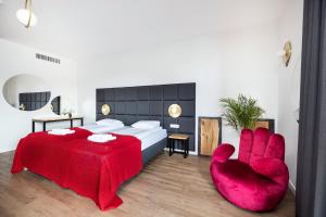 a bedroom with a bed and a red chair at Apartamenty Deo Plaza - Old Town in Gdańsk