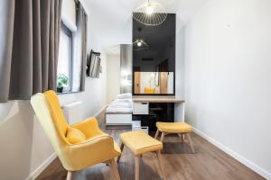 a living room with a yellow chair and a desk at Apartamenty Deo Plaza - Old Town in Gdańsk
