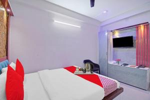 a bedroom with a bed with red pillows and a television at Flagship Diamond Regency Near Birla Mandir in Kolkata