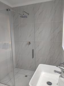 a shower with a glass door next to a sink at Aloe Studio in Jeffreys Bay