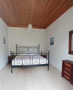 ein schwarzes Bett in einem Zimmer mit Holzdecke in der Unterkunft Lovely Sunrise apartment by the beach in Methoni