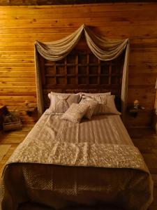 a bedroom with a large bed with a wooden wall at Alto da colina Caraá RS in Caraá