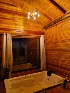 a bath tub in a wooden room with a window at Alto da colina Caraá RS in Caraá +38 photos
